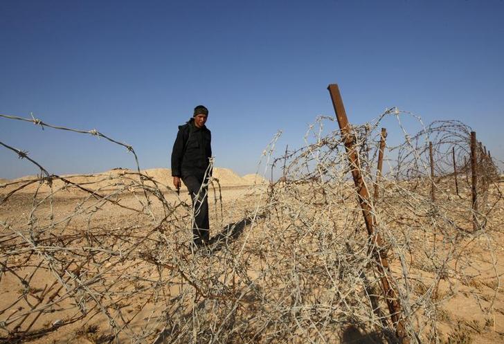 An Egyptian soldier stands behind a barbed wire fence on the border between Israel and Egypt, north of Eilat
