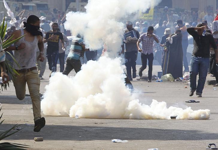 Protesters who support former Egyptian President Mohamed Mursi react to tear gas fired by riot police during clashes outside the Republican Guard building in Cairo