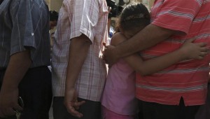 A girl hugs her father as he stands in line before casting his vote outside a polling station in Cairo