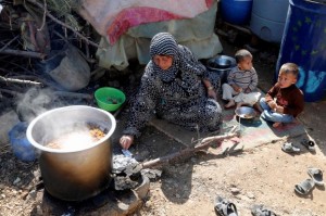 Syrian refugees rest while cooking a meal at an informal settlement in Zahle