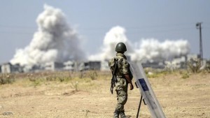 A picture taken from the Turkish side of the border in Suruc, Sanliurfa province, shows a Turkish solider standing as smoke rises from the Syrian town of Kobane, also known as Ain al-Arab, on June 27, 2015, a day after a deadly suicide bombing occurred. The Islamic State group killed 164 civilians in its offensive on the Kurdish town of Kobane, in what a monitor Friday called one of the jihadists' "worst massacres" in Syria. AFP PHOTO/BULENT KILIC        (Photo credit should read BULENT KILIC/AFP/Getty Images)