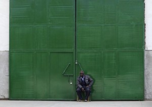 A guard sits in front of one of the gates of a metal factory, which is operating with few workers, on the outskirts of Cairo, February 26, 2013. Countrywide, the report estimates over 4,500 factories have shut since the revolution, swelling by hundreds of thousands the ranks of unemployed in a nation where two-fifths of the people live on or around the poverty line. The unemployment rate is around 13 percent, according to official data, but private analysts believe the actual rate is much higher. Picture taken February 26, 2013. To match story EGYPT-INDUSTRY/ REUTERS/Asmaa Waguih  (EGYPT - Tags: BUSINESS EMPLOYMENT)