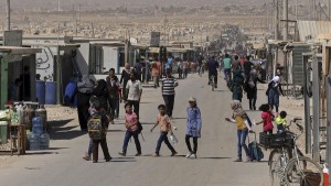 In this Thursday, Oct. 1, 2015 photo, Syrian refugees stroll on the main street of the U.N.-run Zaatari refugee camp near Mafraq, northern Jordan. More than 4 million Syrians fled civil war in their country, now in its fifth year. Most settled in Turkey, Lebanon and Jordan. Banned from working legally, they depend on aid and odd jobs. (AP Photo/Raad Adayleh)